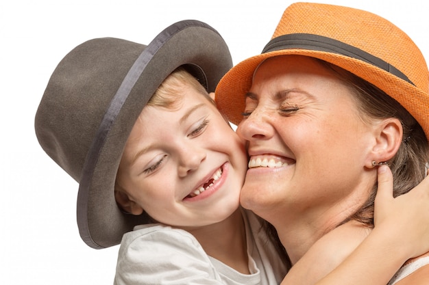 Maman avec un petit fils en chapeaux embrassant et riant, famille mignonne