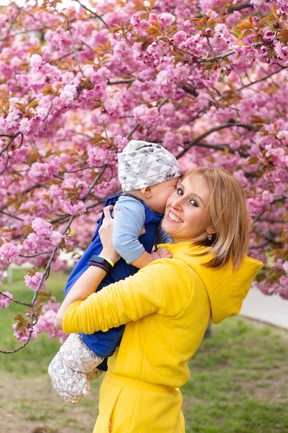 Maman avec petit fils dans le parc jouant près de l'arbre sakura