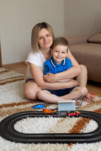 Maman et petit fils jouent à la course sur le tapis à la maison, s'amusent et se font des câlins.