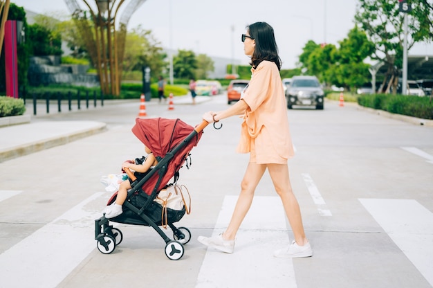 Maman et le petit fils sur la poussette traversent la route