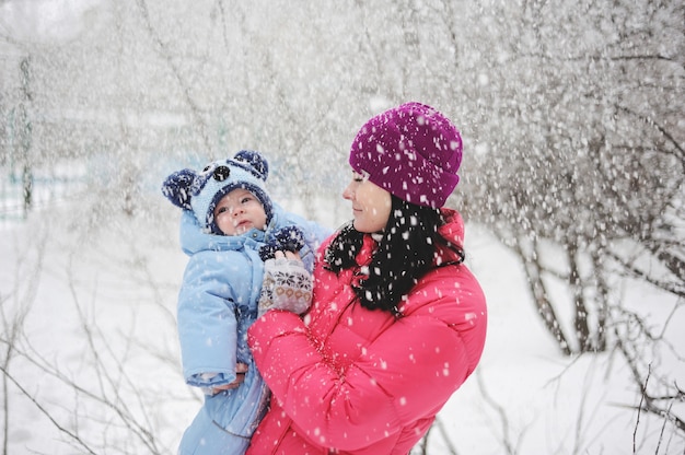 Maman et petit garçon jouant sous la neige. Maman et bébé garçon vêtus de vêtements d&#39;hiver