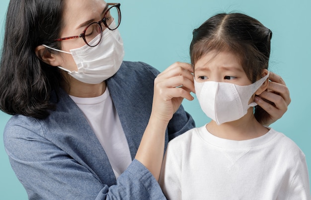 Maman et petite fille asiatique portant des masques médicaux pour se protéger