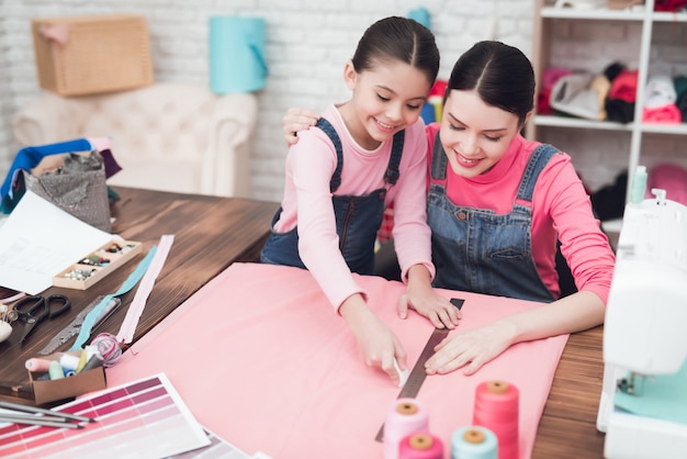 Maman et petite fille cousent ensemble des vêtements.