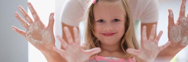 Maman et petite fille montrant les paumes des mains dans la farine