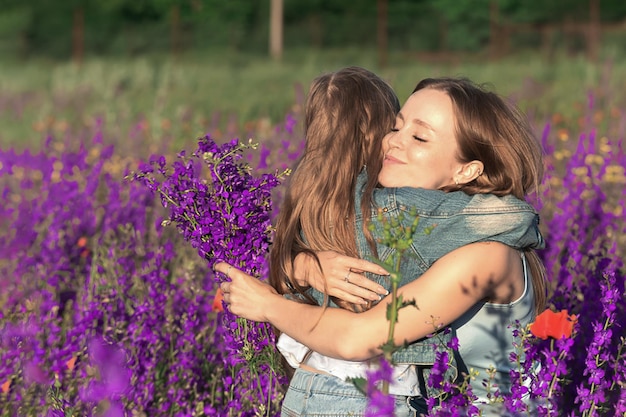 Maman et petite fille s'étreignent dans une clairière de fleurs de lilas sauvages