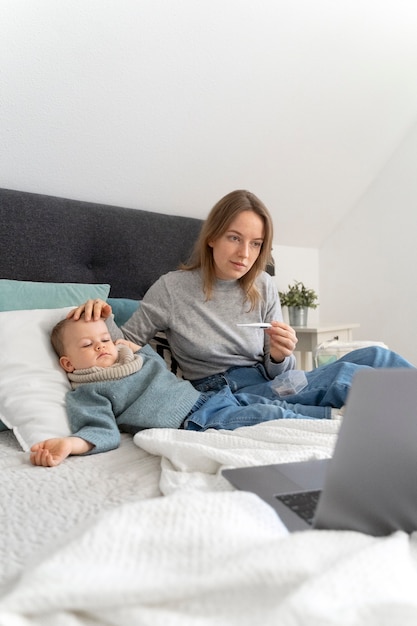 Photo maman prenant soin de son enfant et téléconsultation avec un médecin