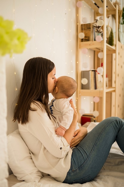 Maman s'assoit avec sa fille sur le lit et l'embrasse.