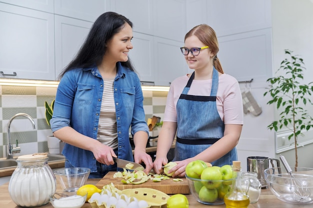 Maman et sa fille adolescente cuisinent ensemble une tarte aux pommes à la maison