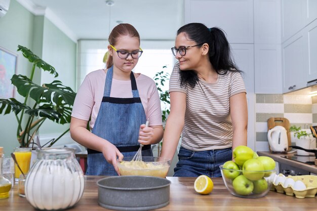 Maman et sa fille adolescente préparent ensemble la tarte aux pommes