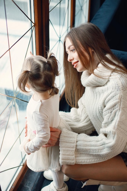 Maman et sa fille debout et regardant dans une grande fenêtre