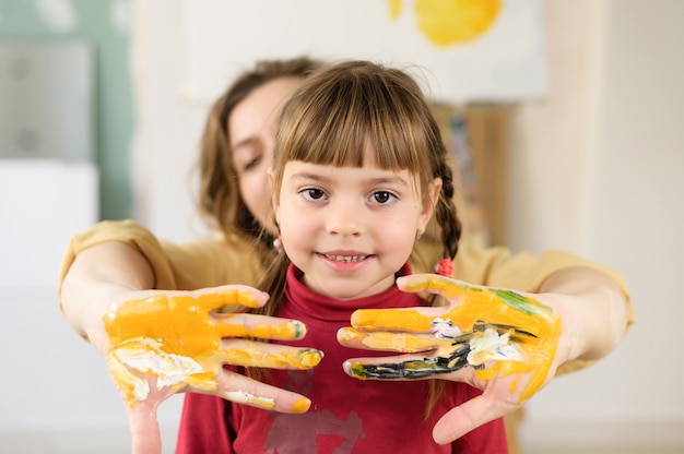 Maman avec sa fille étend ses mains, tachées de peinture