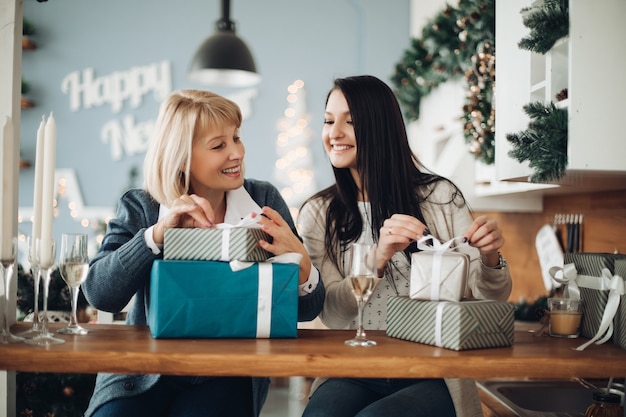 Une maman et sa fille heureuses déballent les cadeaux de Noël