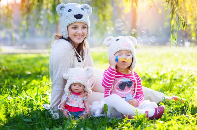 Maman et sa fille jouant dans le parc avec une poupée en casquettes