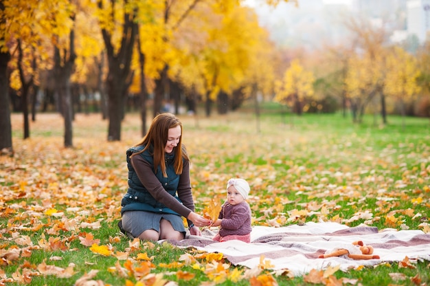 Maman et sa fille jouent dans le parc d'automne. Une famille heureuse.