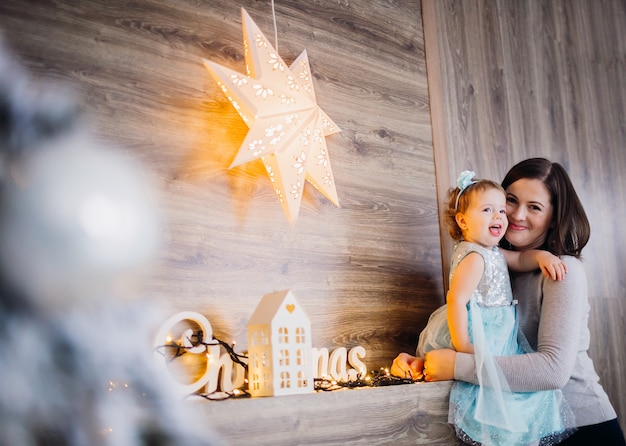 Maman et sa fille jouent avec une étoile brillante sur la cheminée