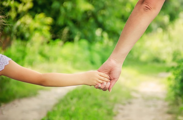 Maman et sa fille marchent le long de la route en se tenant la main.