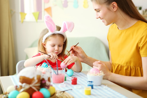 Maman et sa fille peignent des œufs de pâques pour les traditions de pâques de vacances