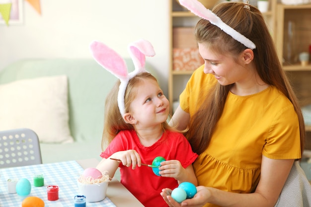 Maman et sa fille peignent des œufs de pâques pour les traditions de pâques de vacances