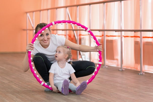 Maman et sa fille pratiquent un sport avec un cerceau.