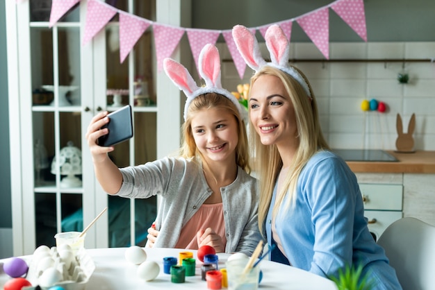 Maman et sa fille prennent des selfies dans les oreilles de lapin de Pâques.