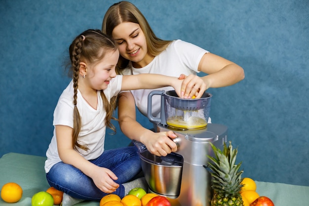 Maman Et Sa Fille Préparent Une Orange Fraîche. Ils Sont En T-shirts Blancs.