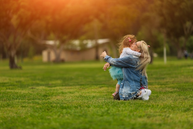 Maman et sa fille rient et s'embrassent dans le parc en été