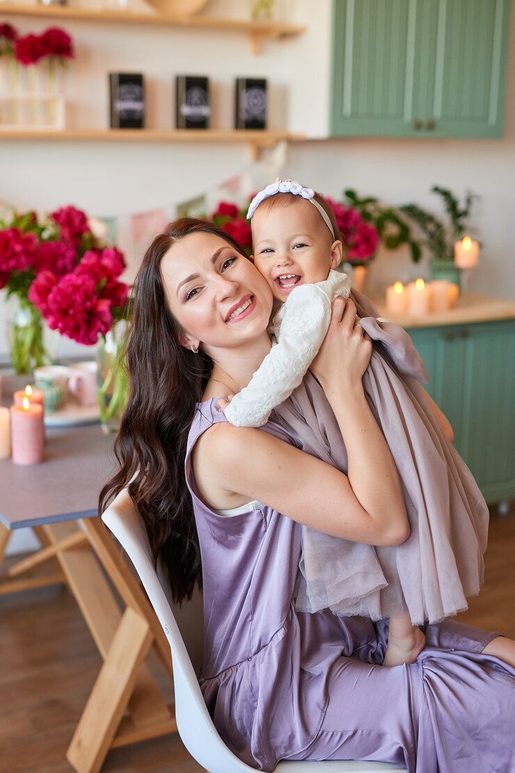 Photo maman et sa fille en robes élégantes dans la cuisine, décorées de pivoines