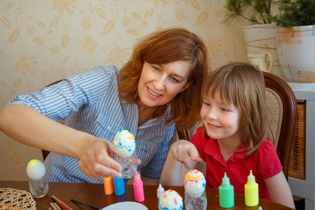 Maman et sa fille s'amusent à peindre des œufs pour Pâques.