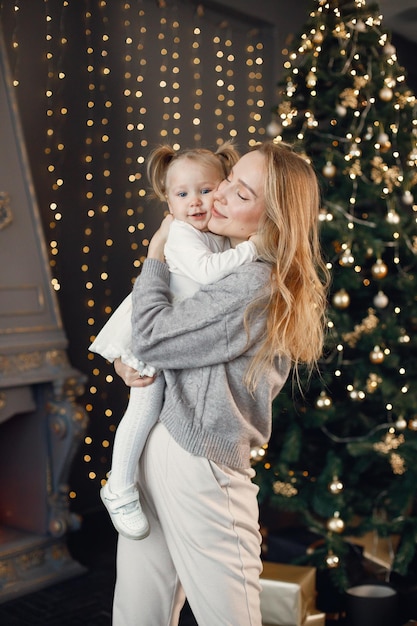 Maman et sa fille s'embrassent près du sapin de Noël