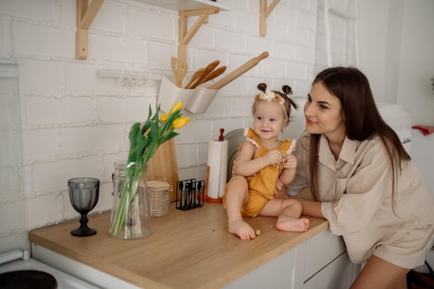 Photo maman et sa fille se font un câlin dans la cuisine vie de famille à la maison