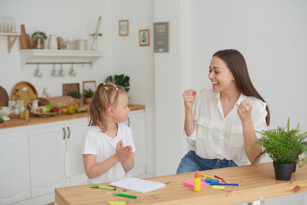 Maman et sa fille sont heureuses de finir leurs devoirs dans la cuisine. La vie à la maison. Une vraie joie.