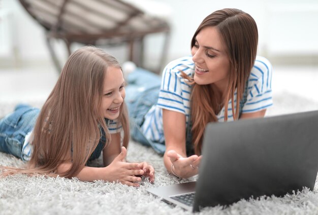 Maman et sa petite fille discutent de quelque chose en regardant l'ordinateur portable