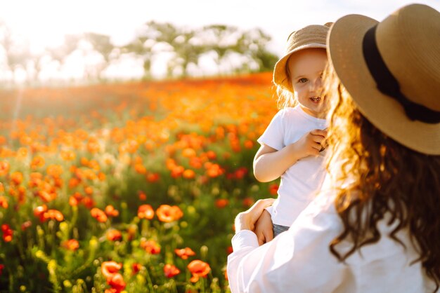 Maman et sa petite fille jouent dans le champ de coquelicots en fleurs