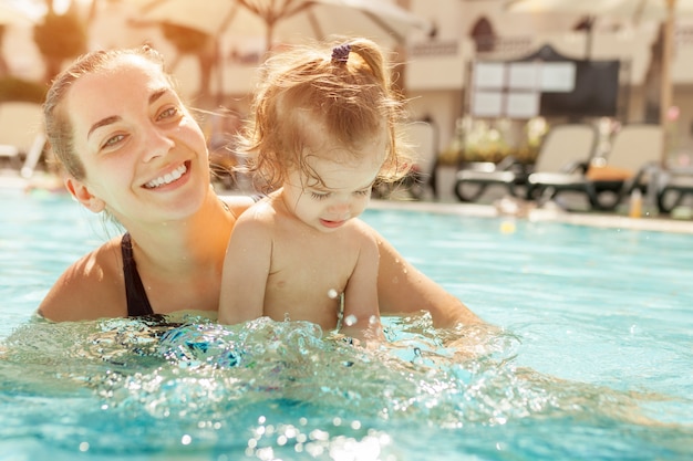 Maman et sa petite fille jouent dans la piscine ouverte.