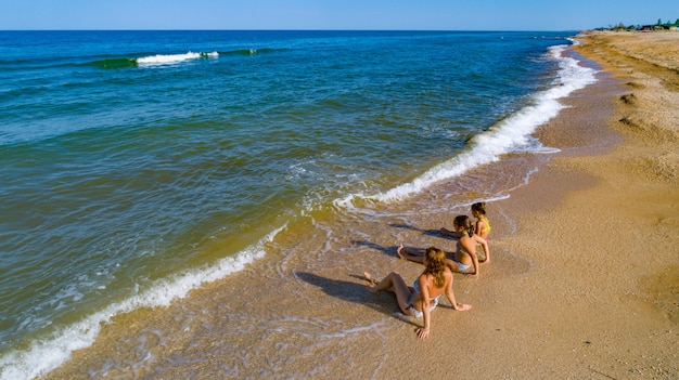 Maman et ses filles profitant de la vue sur la mer assis au bord de la mer dans les vagues