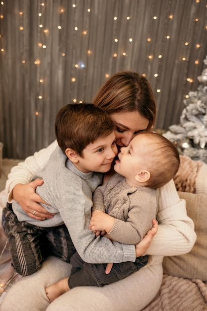 Maman et ses fils sont assis sur le canapé et s'embrassent sur fond de nouvel an