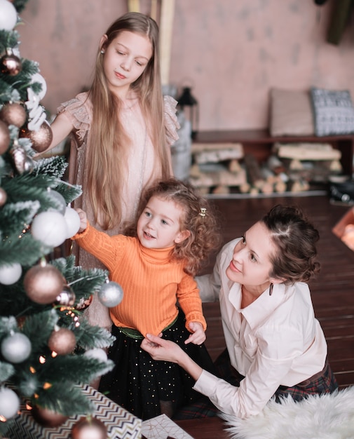 Maman et ses petites filles décorant le sapin de Noël. concept de vacances