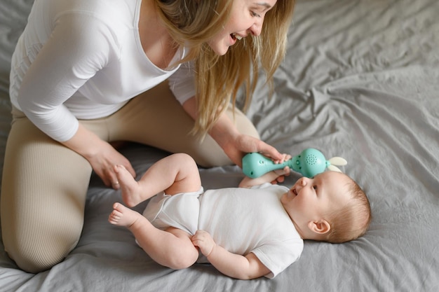 Maman et son adorable bébé jouent avec un hochet pour développer la motricité fine du