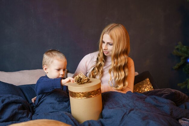 Maman et son fils assis sur le lit en ouvrant des cadeaux