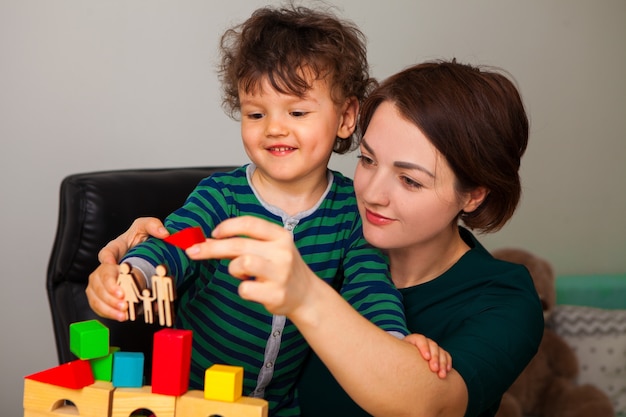 Maman et son fils construisent une maison pour la famille. Ils ont mis un toit. Une femme montre et enseigne au garçon combien il est important de mettre en quarantaine à la maison.