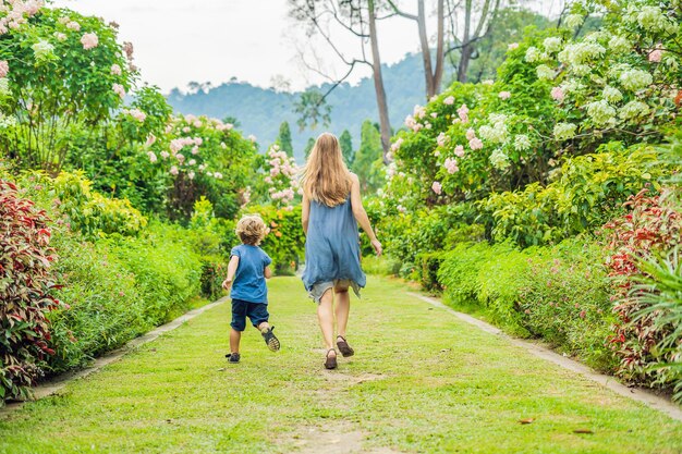 Maman et son fils courent dans le jardin fleuri. Concept de style de vie de famille heureux