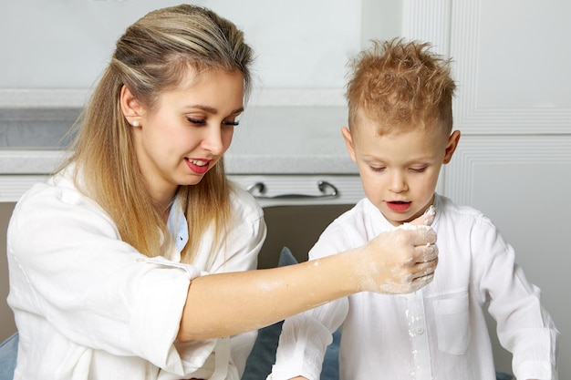 Maman et son fils cuisinent ensemble dans une cuisine blanche à partir de pâte