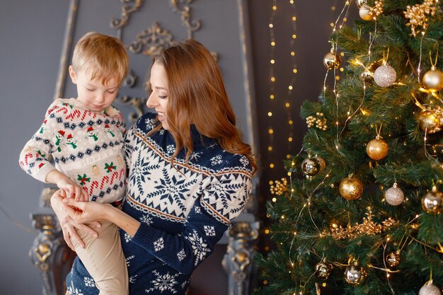 Maman et son fils debout près du sapin de Noël et se serrant dans leurs bras