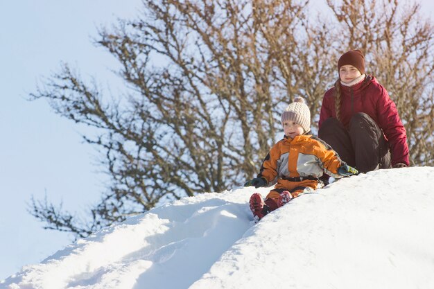 Maman et son fils descendent une pente de neige.