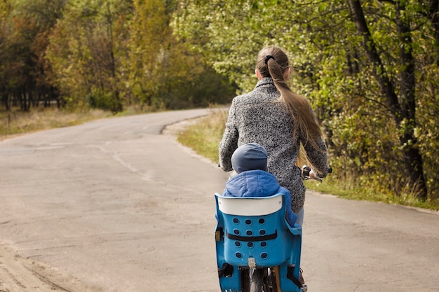 Maman et son fils font du vélo sur la route d'automne. Vue arrière.