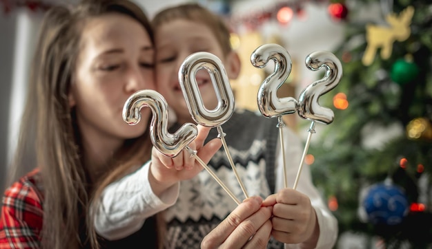 Une maman et son fils heureux sur le fond d'un arbre de Noël tiennent dans leurs mains les numéros d'argent 2022 sur des bâtons. Concept du nouvel an, ambiance festive, décoration de la maison, félicitation