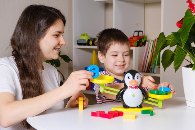 Maman et son fils jouent avec les chiffres, pèsent sur une balance-jouet.