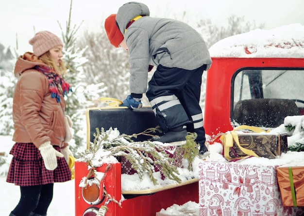 Photo maman et son fils jouent ensemble sur une voiture de vacances avec des cadeaux. la famille prépare la nouvelle année ensemble. hiver enneigé à l'extérieur.