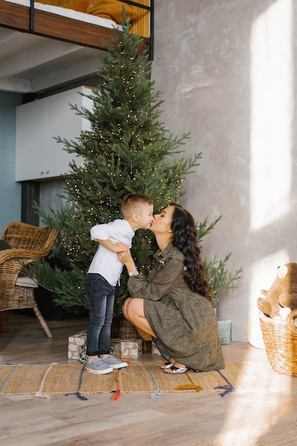 Maman et son fils s'embrassent en prévision des vacances de Noël du Nouvel An près de l'arbre de Noël