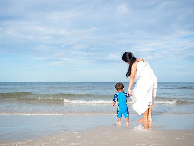 Maman et son fils se tiennent sur la belle plage avec des vagues de merOcean land scape vacances en famille